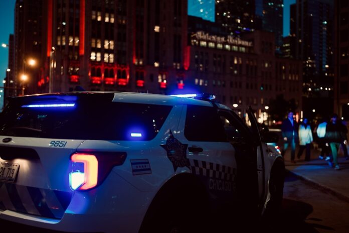 Carro de polícia com luzes piscando em via urbana à noite