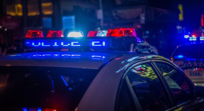 Viatura policial com giroflex vermelho e azul acionado à noite